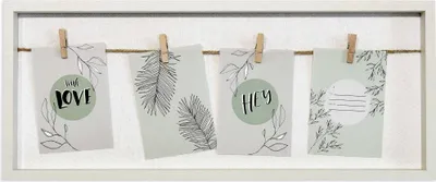 A framed collage of four small cards hanging on a string with clothespins.