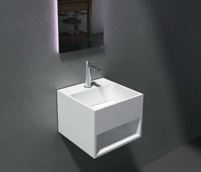 A modern white wall-mounted sink with a chrome faucet against a textured gray wall.