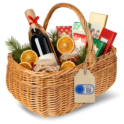 A wicker gift basket filled with holiday items, including a bottle of wine, dried oranges, small jars, and gift-wrapped boxes.