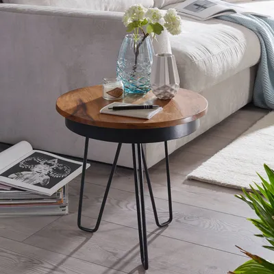 A small round side table with decorative items on top, placed next to a sofa and a rug.