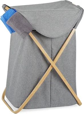 A grey fabric laundry basket with wooden cross supports, holding two folded towels.