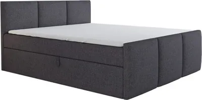 A dark gray upholstered boxspring bed with a white mattress and a visible storage drawer.