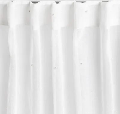 A close-up view of white voile curtains with small pearl embellishments.