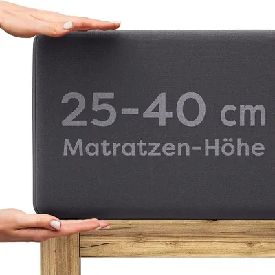 Hands demonstrating the size of a mattress topper on a wooden bed frame.