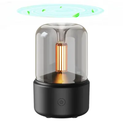 A product shot of a black and clear aroma diffuser with a gold element inside, set against a white background. There are stylized green leaves and blue swirls above the diffuser, suggesting air circulation or fragrance diffusion.