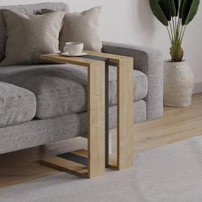 A side table next to a sofa with pillows, a cup of coffee, and a plant in the background.
