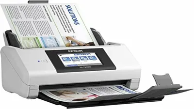 A white Epson document scanner is shown from a three-quarter front view, with documents loaded in the feeder and output tray.