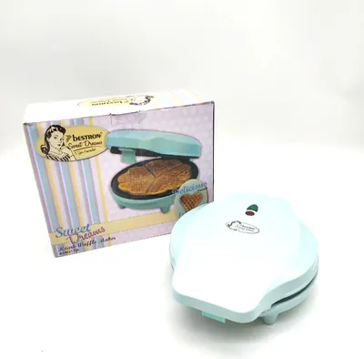 A light blue heart-shaped waffle maker and its packaging are displayed on a white background.