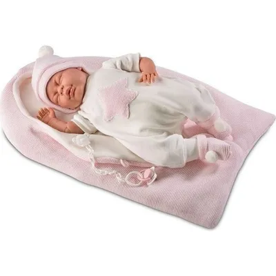 A baby doll sleeping in a pink bassinet.