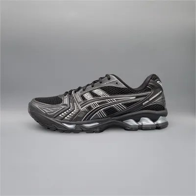 A side view of a black and silver ASICS running shoe against a plain gray background.