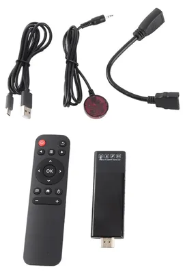A collection of electronic accessories including a remote control, a streaming stick, and various cables, laid out on a white background.