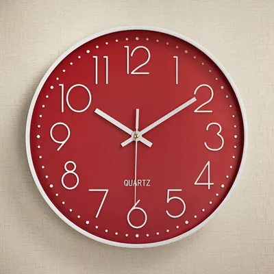 A red wall clock with white numbers and hands is mounted on a textured light beige wall.