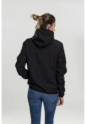 A woman is shown from the back wearing a black windbreaker jacket and blue jeans against a white background.