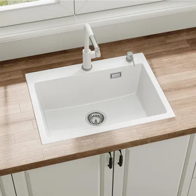 A white kitchen sink with a white faucet and soap dispenser, installed on a wooden countertop.
