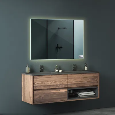 A modern bathroom vanity with a large LED mirror above it.