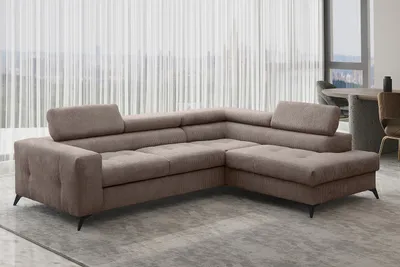 A sectional sofa is shown in a living room setting with sheer curtains in the background.