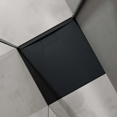 A black shower tray in a corner of a bathroom with gray tiled walls.