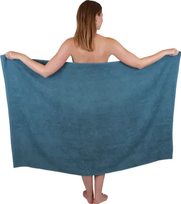 A woman is holding a large blue towel in front of her.