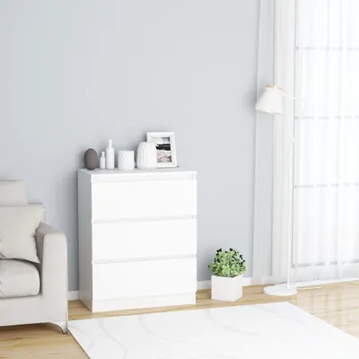 A white chest of drawers with decorative items on top, placed next to a sofa and in front of a window with sheer curtains. A rug is on the floor.