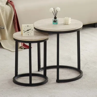 Two nesting side tables with wood-look tops and black metal frames are placed on a light-colored rug.