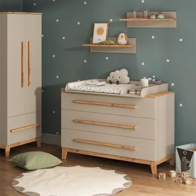 A nursery room with a changing table, wardrobe, and decorative elements.