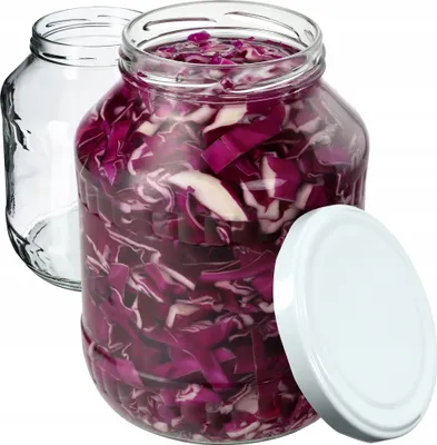 Two glass jars, one filled with chopped red cabbage and the other empty, with a white lid placed next to the filled jar.