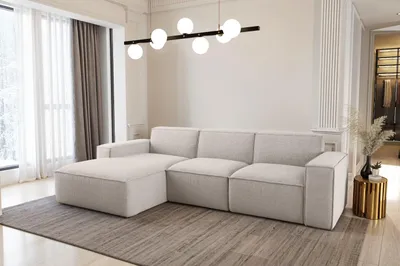 A modern living room with a sectional sofa, a chandelier, and a side table.
