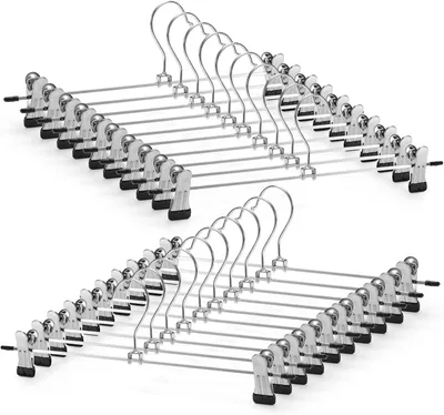 A stack of metal hangers with clips against a white background.