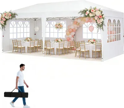A white party tent set up for an event with tables, chairs, and decorations.