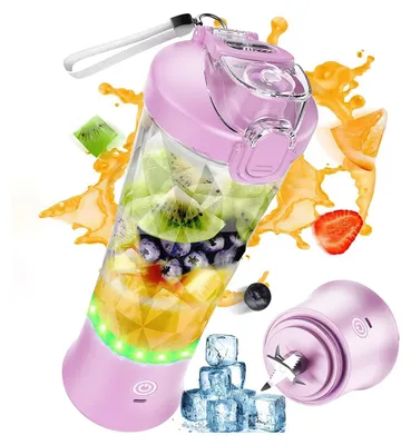 A pink portable blender filled with fruit and surrounded by splashes of juice and ice cubes.