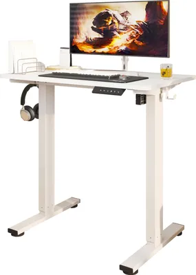 A white electric standing desk with a monitor, keyboard, and headphones.