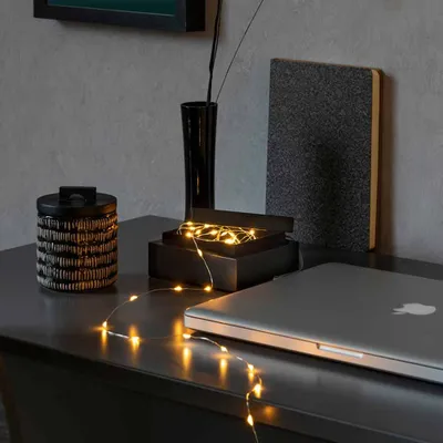 A desk setup with a laptop, decorative items, and string lights.
