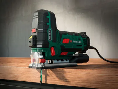 A Parkside jigsaw is placed on a wooden surface with a concrete wall in the background.