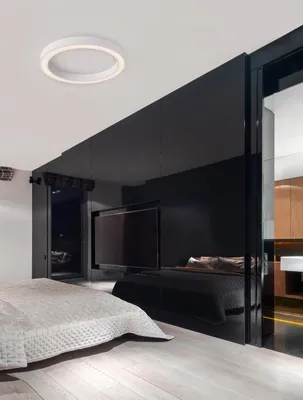 A modern bedroom with a large black mirrored wall reflecting a television and another bed.