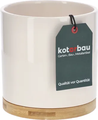 A cream-colored ceramic pot with a bamboo base, featuring a dark green tag with brand information and a slogan.