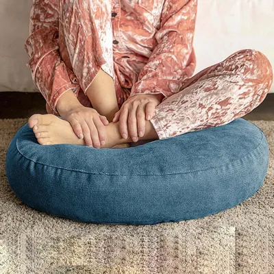 A person sitting on a floor cushion, wearing pajamas.