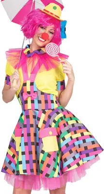 A woman dressed in a colorful clown costume, holding a pink and white umbrella and a lollipop.