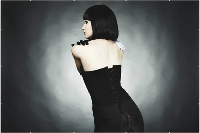 Produktbild von Wallario Wandbild Schöne Frau im schwarzen Kleid zeigt ihren Rücken, Größe: 61 x 91,5 cm, Poster mit rahmenlosen Bildhalter