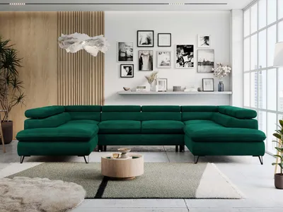 A spacious living room with a large, U-shaped green sofa as the centerpiece, decorated with framed pictures on the wall and a round coffee table.