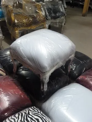 A collection of upholstered ottomans wrapped in plastic, stacked together indoors.