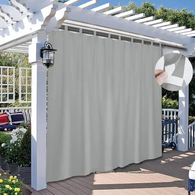 An outdoor patio with a pergola covered by a gray curtain.