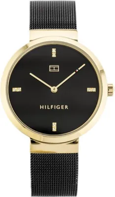 A close-up studio shot of a Tommy Hilfiger women's watch with a black dial and gold-tone case and mesh strap.