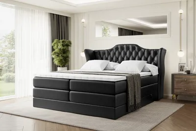 A bedroom scene with a large black upholstered bed as the main focus.