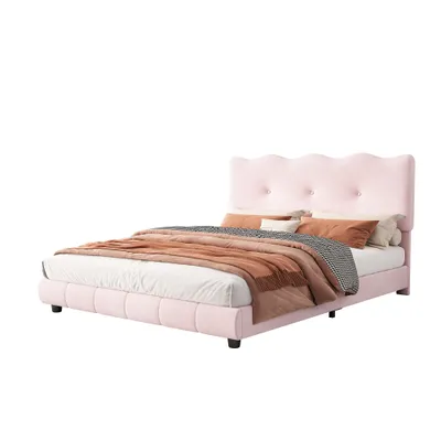 A pink upholstered bed with a scalloped headboard and bedding.