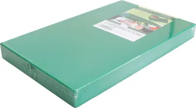 A green cutting board wrapped in plastic packaging, shown at an angle on a white background.