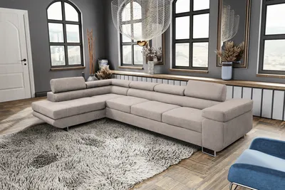 A spacious living room with a large sectional sofa, a fluffy rug, and arched windows.