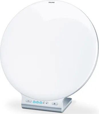 A white, circular light therapy lamp with a silver base is shown against a white background.