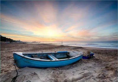 Produktbild von Wallario Fototapete Vliestapete, seidenmatte Oberfläche, einfache Verarbeitung, Größe 200 x 140 cm, Motiv Fischerboot am Strand bei Sonnenuntergang