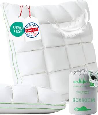 A white pillow and a rolled-up pillow in its packaging, with certification tags and a feather.