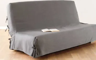 A grey sofa cover is shown on a sofa, with a book placed on top.